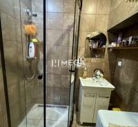 Na predaj 2 izbový byt  na Sokolovskej ulici v meste Humenné - Kúpeľňa v 2-izbovom byte so sprchovým kútom, umývadlom a hnedými obkladmi.