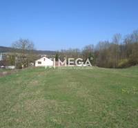 ZNÍŽENIE CENY-PREDAJ VEĽKÉHO POZEMKU (7.048 m2) v  obci Tovarnianska P - Pozemky - bývanie v Tovarnianskej Polianke, s výhľadom na domy a stromy pod modrou oblohou.