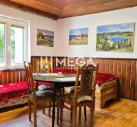 PREDAJ REKREAČNEJ CHATY NA DOMAŠI časť DOBRÁ - Izba na chate s dreveným stropom a podlahou s dreveným dekorom, obrazy na stenách.