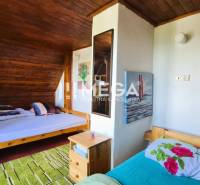 PREDAJ REKREAČNEJ CHATY NA DOMAŠI časť DOBRÁ - Interiér chaty s dreveným obkladom, dvoma posteľami a nočným stolíkom.