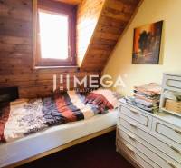 PREDAJ REKREAČNEJ CHATY NA DOMAŠI časť DOBRÁ - Izba v chate s posteľou, drevenými stenami a komodou.