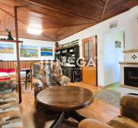 PREDAJ REKREAČNEJ CHATY NA DOMAŠI časť DOBRÁ - Chata s krbom a podlahou s dreveným dekorom, sedačkou a dekoratívnymi obrazmi.