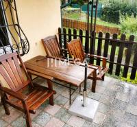 PREDAJ REKREAČNEJ CHATY NA DOMAŠI časť DOBRÁ - Drevený nábytok na terase chaty na Vodárenskej ulici v Kvakovciach, s výhľadom na záhradu.