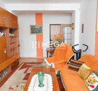 PREDAJ 3-izbového bytu v Medzilaborciach (TOP CENA) - Obývacia izba v 3-izbovom byte s hnedým nábytkom a oranžovými doplnkami, podlaha s dreveným dekorom.