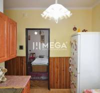 PREDAJ 3-izbového bytu v Medzilaborciach (TOP CENA) - Kuchyňa v 3-izbovom byte s dreveným dekorom, chladničkou a keramickými hrnčekmi.