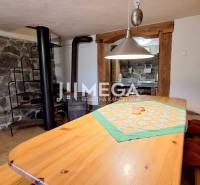 EXKLUZÍVNE NA PREDAJ Chata bez nutnosti investícií - VINNÉ - Kamenný interiér chaty so špirálovým schodiskom a dreveným stolom s dekoratívnym obrúskom.