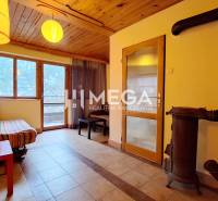 EXKLUZÍVNE NA PREDAJ Chata bez nutnosti investícií - VINNÉ - Interiér Chaty s posedením, kachľami a oknami na terasu, podlaha s dreveným dekorom.