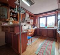 SKVELÁ CENA - výnimočný  rodinný dom, Kamenica nad Cirochou - Kuchyňa v rodinnom dome s podlahou s dreveným dekorom, drevenými skrinkami a oknom.