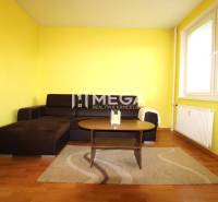 REZERVOVANÝ 3-izb. BYT – SÍDLISKO III, HUMENNÉ LABORECKÁ ul. - Obývacia izba v 3-izbovom byte s podlahou s dreveným dekorom, žlté steny, sedačka.