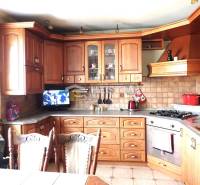 ZNÍŽENÁ CENA Veľký 2-izbový investičný byt Senica - 73,54 m² - Kuchyňa s drevenými skrinkami v 2-izbovom byte, keramický obklad, televízor, kuchynský riad.