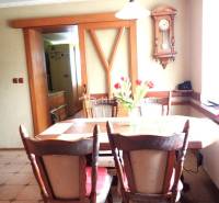 ZNÍŽENÁ CENA Veľký 2-izbový investičný byt Senica - 73,54 m² - Jedáleň v 2-izbovom byte s dreveným stolom, retro hodiny na stene.