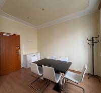 Prenájom kancelárie 33 m2 v centre Piešťan - Kancelárie s podlahou s dreveným dekorom, čiernym stolom a bielymi stoličkami.