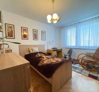 Na predaj: 4 izb.byt + BALKON + ŠATNIK + ŠPAJZA - Spálňa v 3-izbovom byte s podlahou s dreveným dekorom, nábytkom a hojdacím kreslom.