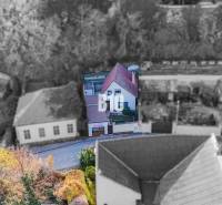 POD HRADOM bývanie alebo podnikanie - Rodinný dom v Nitre s červenou strechou a záhradou obklopenou stromami.