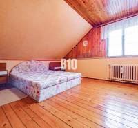 POD HRADOM bývanie alebo podnikanie - Podkrovná izba s dvojlôžkovou posteľou, dreveným stropom a podlahou s dreveným dekorom.