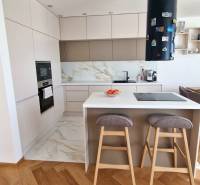 PRENÁJOM - 4 izbový rodinný dom, ktorý je súčasťou dvojdomu   - Kuchyňa v rodinnom dome s ostrovčekom a podlahou s dreveným dekorom.