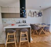 PRENÁJOM - 4 izbový rodinný dom, ktorý je súčasťou dvojdomu   - Kuchyňa a jedáleň s ostrovčekom, barovými stoličkami a podlahou s dreveným dekorom v rodinnom dome.
