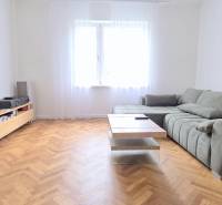 Pekný 3i byt, REKONŠTRUKCIA, KLÍMA, NIVY, Trenčianska ulica - Svetlá obývačka v 3-izbovom byte s pohodlnou sedačkou, stolíkom a výhľadom na ulici Trenčianska.