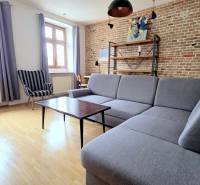 JEDINEČNÝ 2i byt, REKONŠT., 2 X .SAMOST.IZBA, Hviezdoslavovo nám.  - Obývačka vo svetlých tónoch s pohovkou a tehlovou stenou v 2-izbovom byte.