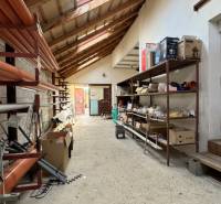 NA PREDAJ rodinný dom/polyfunkcia Komjatice  - Skladový priestor v rodinnom dome s regálmi a stavebným materiálom.