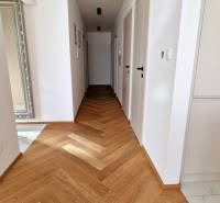 PRENÁJOM - 4 izbový rodinný dom, ktorý je súčasťou dvojdomu   - Chodba s podlahou s dreveným dekorom v rodinnom dome, biele steny, zrkadlo a dvere.