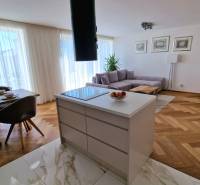 PRENÁJOM - 4 izbový rodinný dom, ktorý je súčasťou dvojdomu   - Otvorený priestor v rodinnom dome s kuchyňou, jedálenským stolom a podlahou s dreveným dekorom.