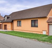 NOVÁ CENA - 5-izbový rodinný dom, dve garáže a krásny pozemok Špačince - Rodinný dom na ulici v Špačinciach so sedlovou strechou a oranžovou fasádou.