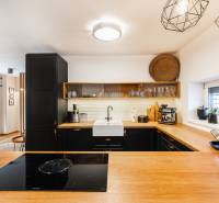 NA PREDAJ Krásny domček v Ivánke pri Nitre - Kuchyňa rodinného domu s dreveným dekorom a čiernymi skrinkami, otvorený priestor.