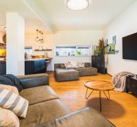 NA PREDAJ Krásny domček v Ivánke pri Nitre - Obývačka v rodinnom dome s kuchynským kútom a podlahou s dreveným dekorom.