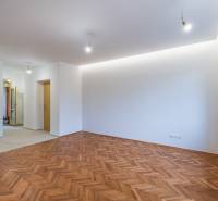 NA PREDAJ štýlový byt v centre Nitry  - Priestranná miestnosť s podlahou s dreveným dekorom v 3-izbovom byte, biele steny a okno.