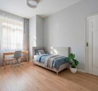 NA PREDAJ štýlový byt v centre Nitry  - Svetlá spálňa s podlahou s dreveným dekorom, posteľou a písacím stolom v 3-izbovom byte.