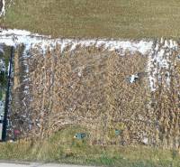 NA PREDAJ Stavebný pozemok v obci Golianovo - Letecký pohľad na pozemky pri Golianove s viditeľným snehom a vychodenými cestami.