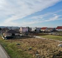 NA PREDAJ Stavebný pozemok v obci Golianovo - Pohľad na obytné pozemky v Golianove so zasneženými trávnatými plochami pri ceste.