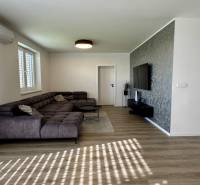 NA PREDAJ 4 izbový rodinný dom Štitáre NITRA - Obývacia izba s rohovou sedačkou, televízorom na stene a podlahou s dreveným dekorom.