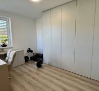 NA PREDAJ 4 izbový rodinný dom Štitáre NITRA - Pracovňa v rodinnom dome s podlahou s dreveným dekorom, minimalistickým stolom a vstavanými skriňami.