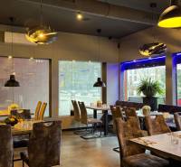 ODSTÚPENIE Gastro prevádzky na Námestí v Nitre - Interiérové gastro priestory s dekoratívnym osvetlením, podlaha s dreveným dekorom, elegantné zariadenie.