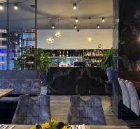 ODSTÚPENIE Gastro prevádzky na Námestí v Nitre - Gastro priestory s podlahou s dreveným dekorom, poličkami na víno a dekoratívnym osvetlením.