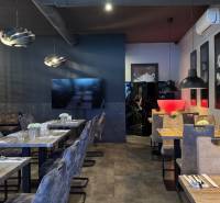 ODSTÚPENIE Gastro prevádzky na Námestí v Nitre - Interiér s podlahou s dreveným dekorom, dekoratívne lustre, elegantné sedenie v gastro priestoroch.