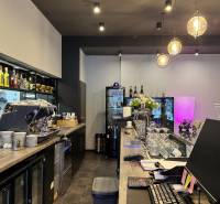ODSTÚPENIE Gastro prevádzky na Námestí v Nitre - Barový pult v gastro priestoroch s nápojmi, kávovarom a pohármi na servírovanie.