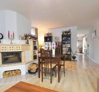 Zaujímavý rodinný dom s veľkým pozemkom, krásnou záhradou a bohatým pr - Interiér rodinného domu s krbom, jedálenským stolom a podlahou s dreveným dekorom.