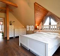 Zaujímavý rodinný dom s veľkým pozemkom, krásnou záhradou a bohatým pr - Podkrovná spálňa v rodinnom dome s dreveným dekorom a bielym nábytkom.