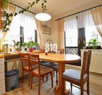 Zaujímavý rodinný dom s veľkým pozemkom, krásnou záhradou a bohatým pr - Interiér rodinného domu so stolom a stoličkami, obklopený izbovými rastlinami.