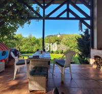 Zaujímavý rodinný dom s veľkým pozemkom, krásnou záhradou a bohatým pr - Terasa rodinného domu v Lietave s výhľadom na kostol, stôl a stoličky.