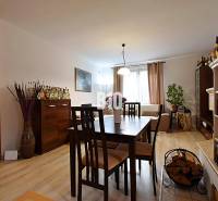 Zaujímavý rodinný dom s veľkým pozemkom, krásnou záhradou a bohatým pr - Interiér rodinného domu s podlahou s dreveným dekorom, jedálenským stolom a krbovými kachľami.