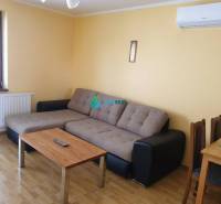 Apartmánový dom na predaj blízko termálneho kúpaliska - Obývacia izba s rohovou pohovkou, stolíkom a klimatizáciou na stene. Vhodná na ulici neuvedené.