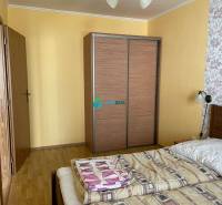 Apartmánový dom na predaj blízko termálneho kúpaliska - Spálňa v byte so žltými stenami a kvetinovou tapetou, s drevenými obchodnými priestormi.