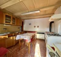 VRAKÚŇ – STARÝ RODINNÝ DOM NA PREDAJ S VEĽKÝM POZEMKOM - 24 ÁROV - Kuchyňa v rodinnom dome so sporákom, digestorom a drevenými skrinkami, podlaha s dreveným dekorom.