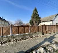 VRAKÚŇ –VEĽKÝ STAVEBNÝ POZEMOK (24 ÁROV) SO STARÝM RODINNÝM DOMOM NA P - Rodinný dom vo Vrakúni s kovovým plotom na neuvedenej ulici, vedľa stromu.