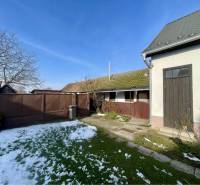 VRAKÚŇ –VEĽKÝ STAVEBNÝ POZEMOK (24 ÁROV) SO STARÝM RODINNÝM DOMOM NA P - Rodinný dom vo Vrakúni s dvorom, bránou, stromom a čiastočne zasneženým trávnikom.