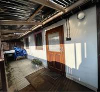 VRAKÚŇ –VEĽKÝ STAVEBNÝ POZEMOK (24 ÁROV) SO STARÝM RODINNÝM DOMOM NA P - Rodinný dom vo Vrakúni s terasou, rastlinou a prestrešením, na dlaždenej podlahe.